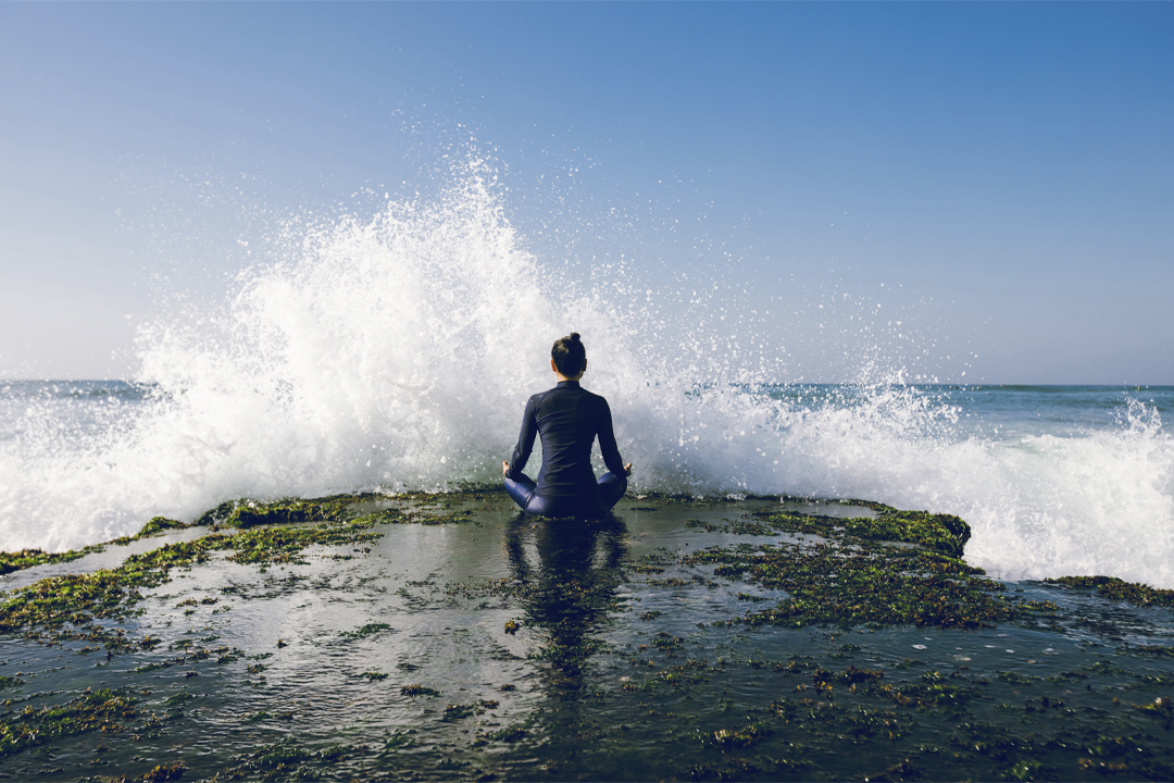 woman-meditation-at-seaside-in-front-of-giant-wave; mehr gelassenheit; Gelassenheit; Gelassenheit steigern