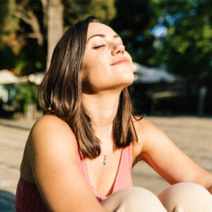 atemübungen bei Stress, Frau sitzt in der Sonne, stressresistenz stärken, Stressresilienz