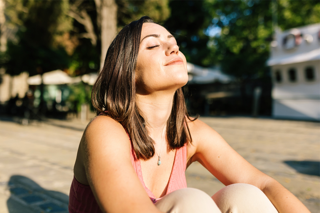 atemübungen bei Stress, Frau sitzt in der Sonne, stressresistenz stärken, Stressresilienz